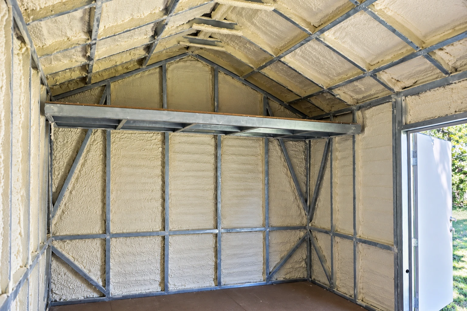 Wall insulation fills a metal-framed room beneath a pitched roof, with an open door at right.